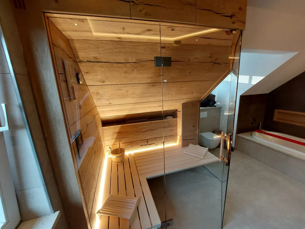 Sauna mit Altholz an Decke und Wand, hellen Bänken und umlaufendem Lichtband vor einer Glasfront
